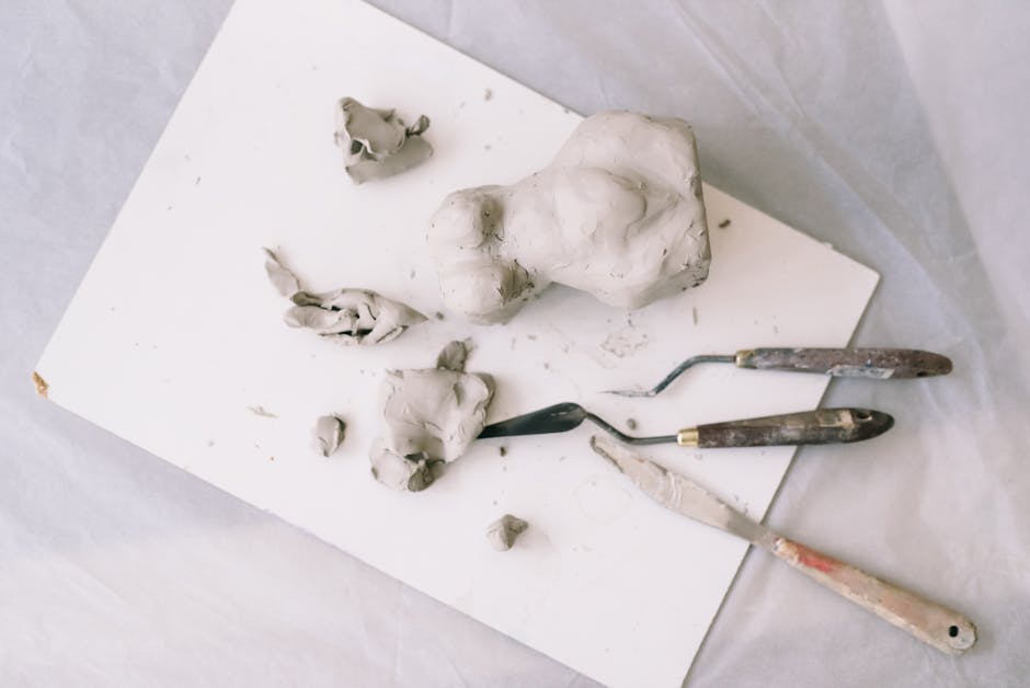 Explore the clay sculpting process with tools and unfinished pieces on a white surface.